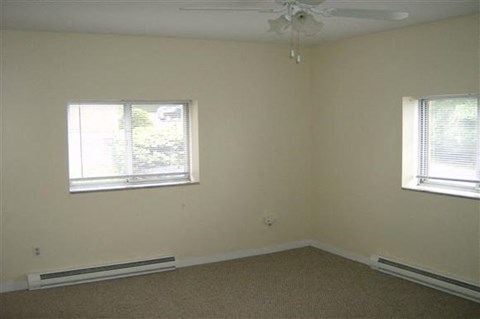 an empty room with two windows and a ceiling fan