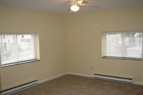 an empty room with two windows and a ceiling fan