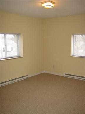 an empty living room with two windows and a carpet