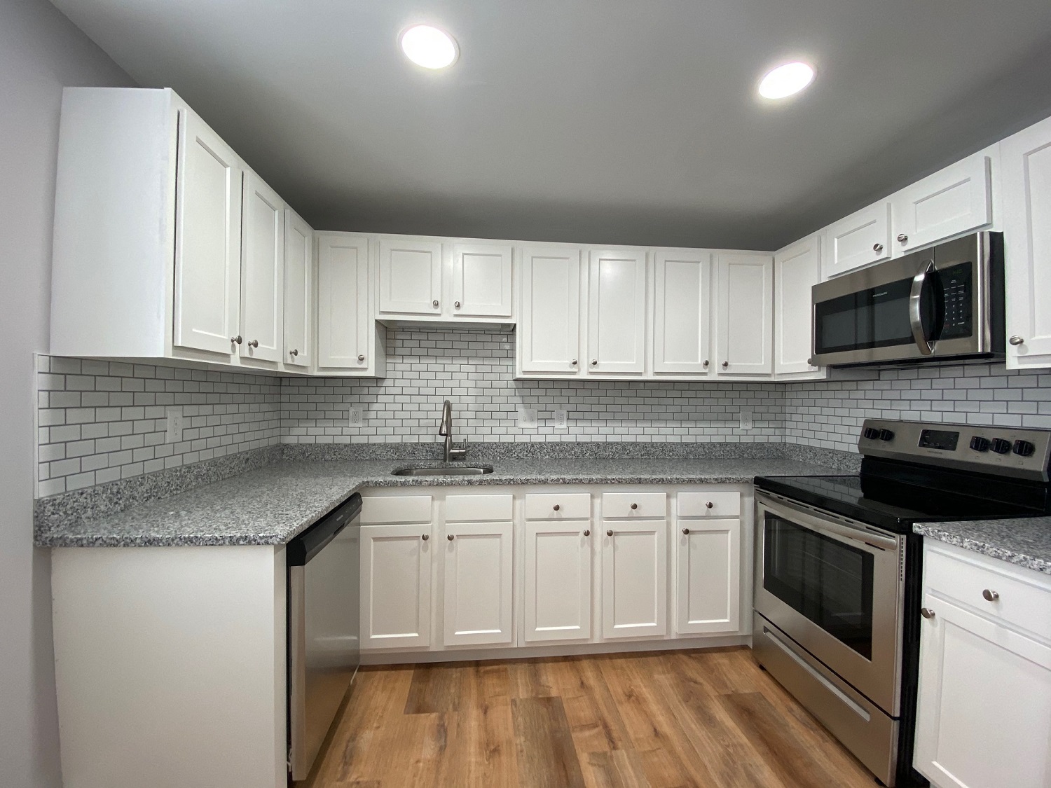 Kitchen with granite counters, white cabinets and stainless appliances