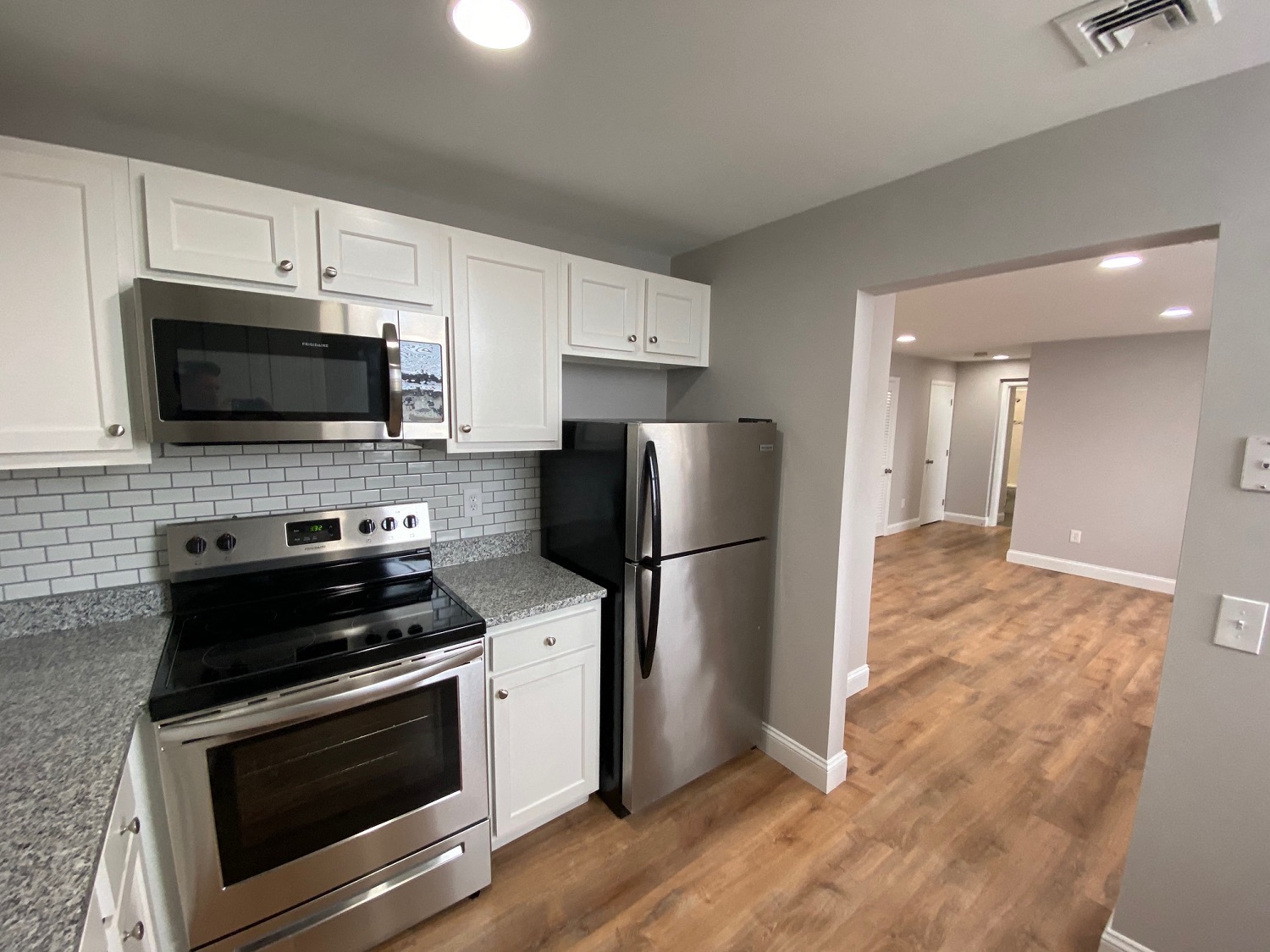 Kitchen with granite counters, white cabinets and stainless appliances
