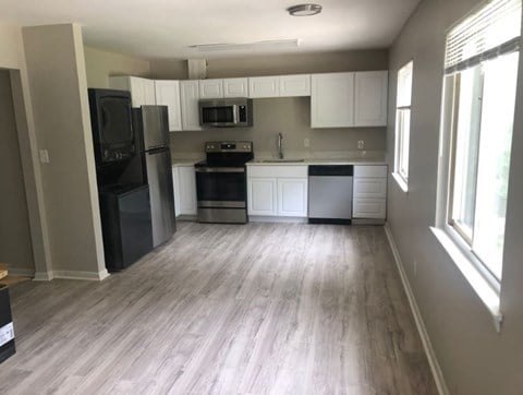 an empty kitchen with white cabinets and stainless steel appliances