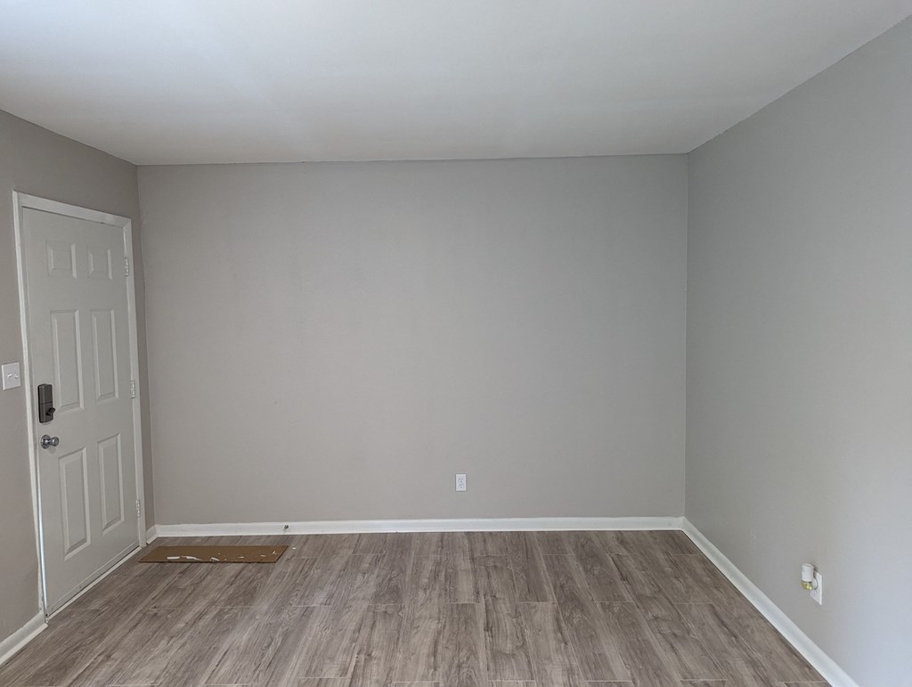 an empty room with wooden floors and a white door
