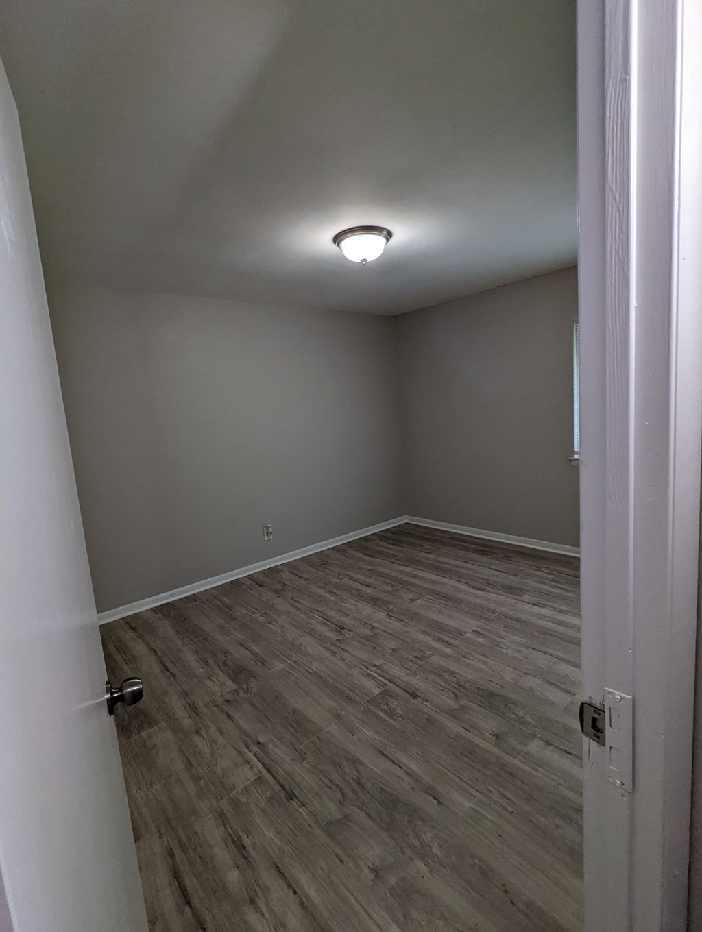 an empty room with wooden floors and a ceiling light