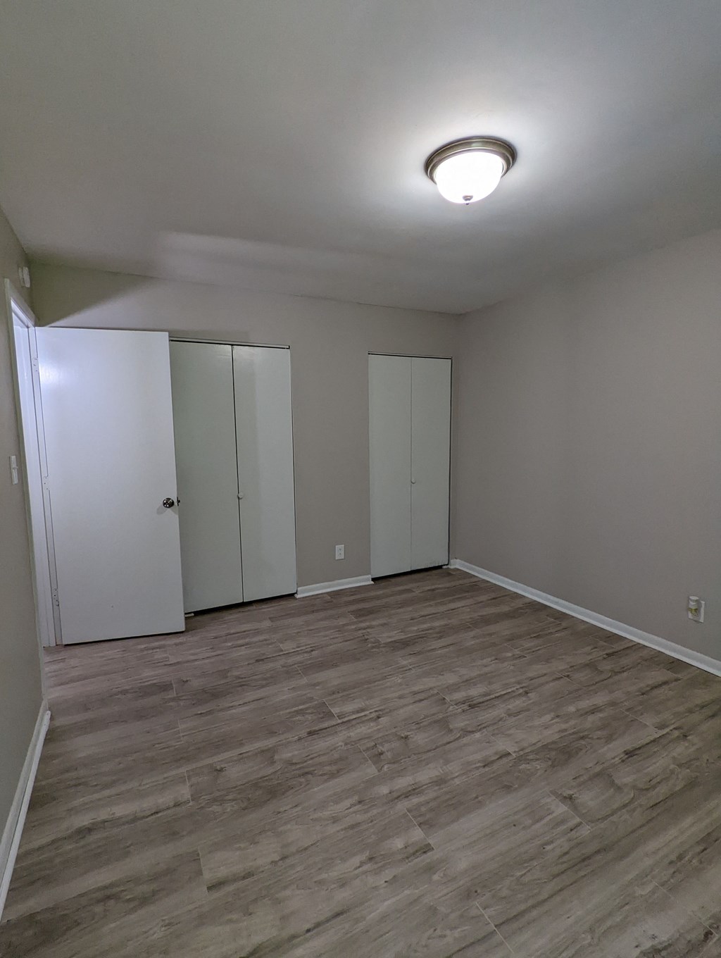 an empty living room with a wood floor and white walls
