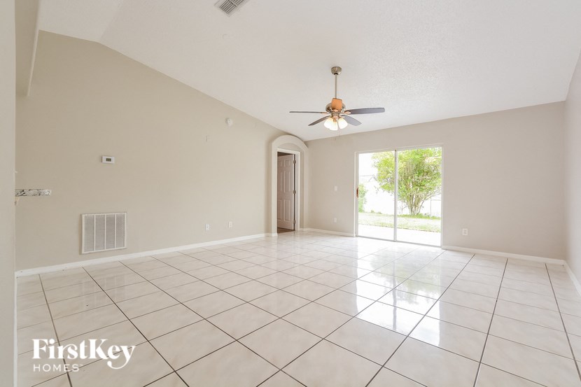 an empty living room with a ceiling fan and tiled floor