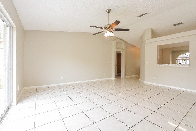 an empty living room with a ceiling fan