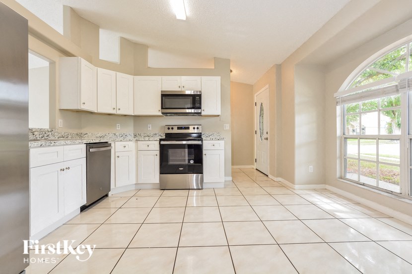 a large kitchen with white cabinets and a large window