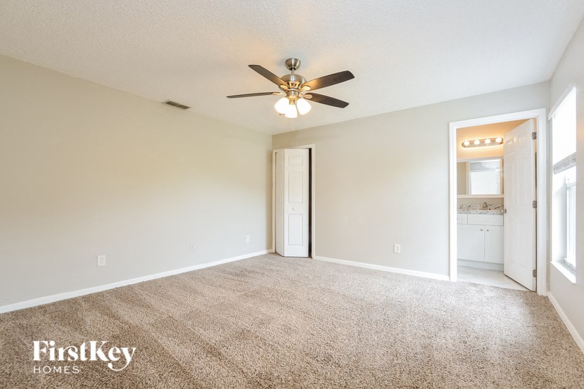 an empty living room with a ceiling fan and a door to a bathroom