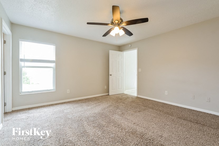 an empty living room with a ceiling fan and a window