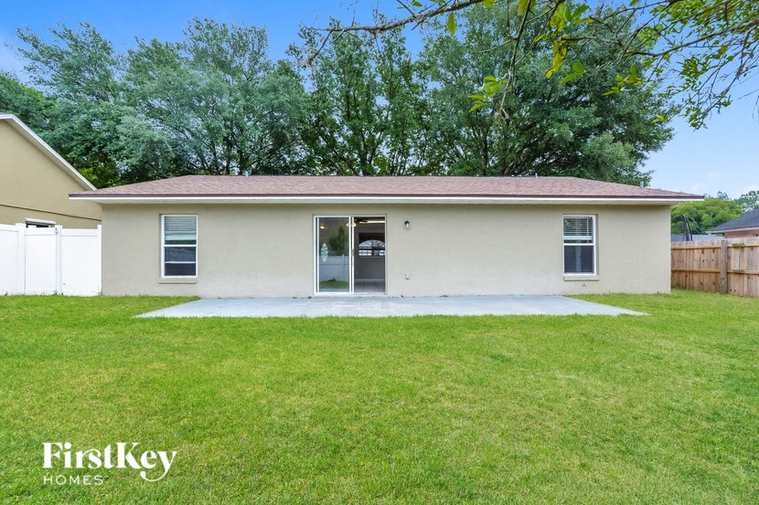 a small white house with a grassy yard and some trees