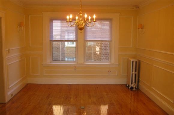 a empty dining room with a window and a chandelier