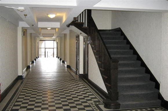 a long hallway with a staircase and a checkered floor
