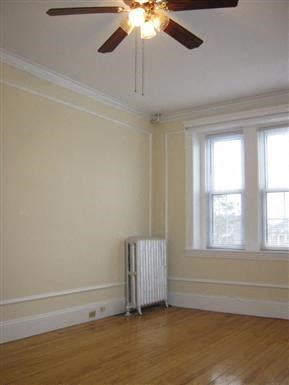 an empty room with a ceiling fan and a radiator