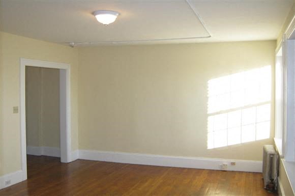 an empty living room with wood floors and a window