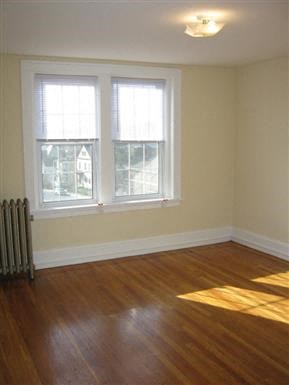 a living room with a wooden floor and two windows