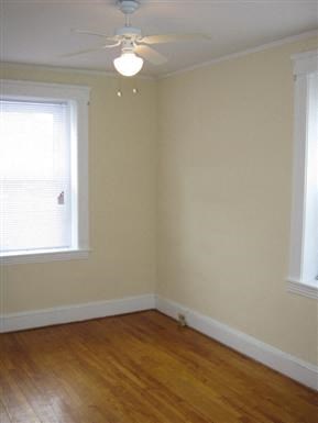an empty room with a ceiling fan and two windows