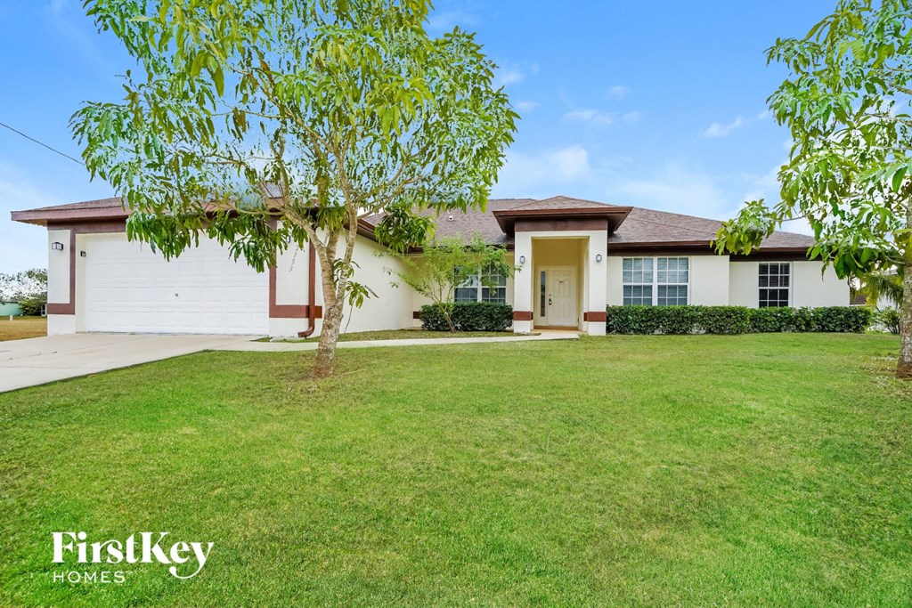a white house with a lawn and a tree