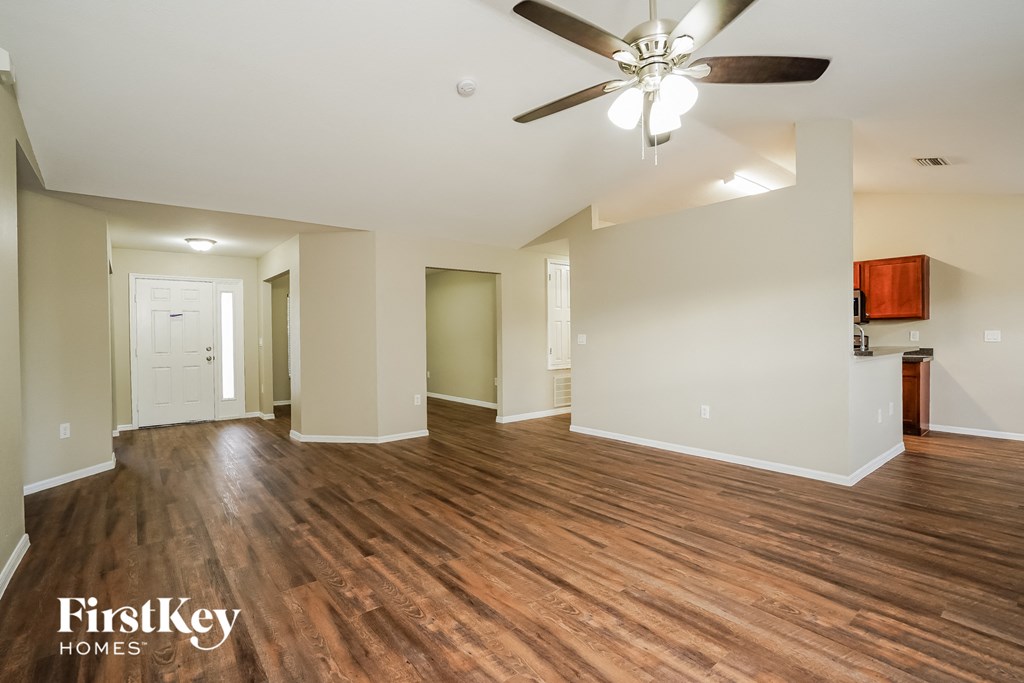 an empty living room with wood flooring and a ceiling fan