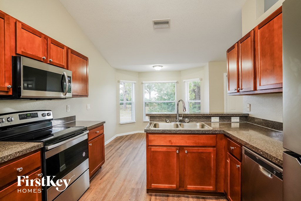 a kitchen with wooden cabinets and granite counter tops and a stove and microwave
