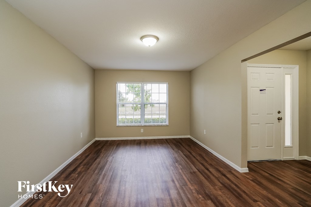 an empty living room with wood flooring and a window