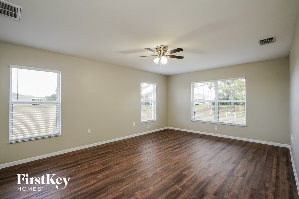 an empty living room with wood floors and a ceiling fan