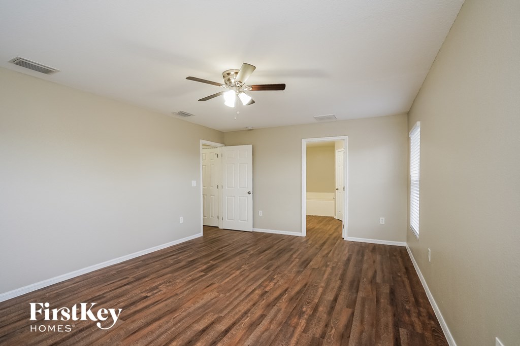 an empty living room with wood flooring and a ceiling fan