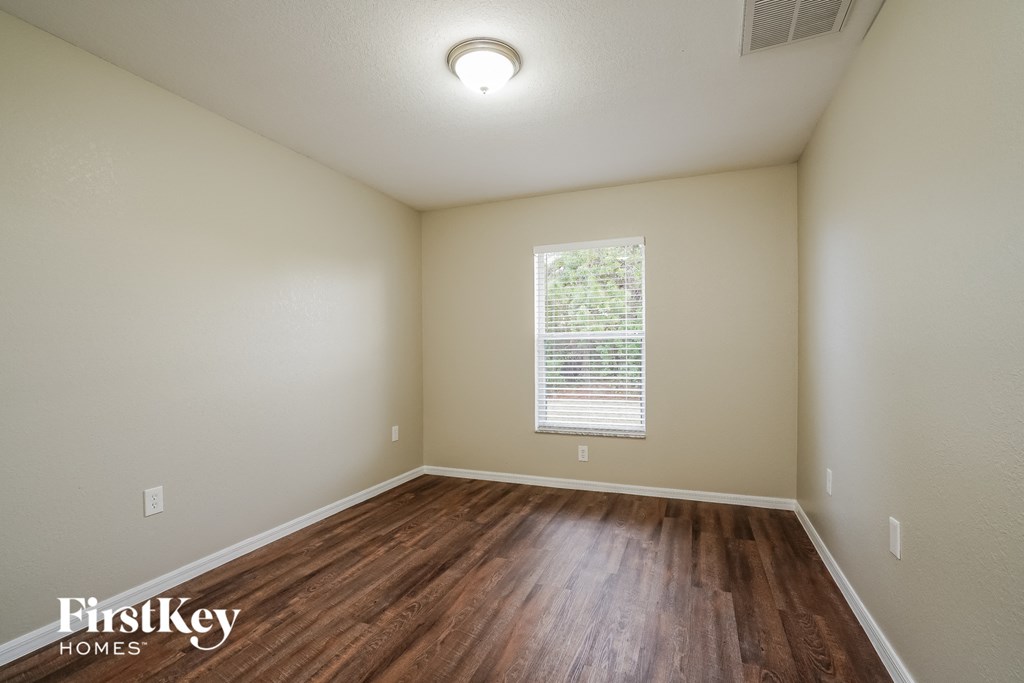 the spacious living room with hardwood flooring and a window