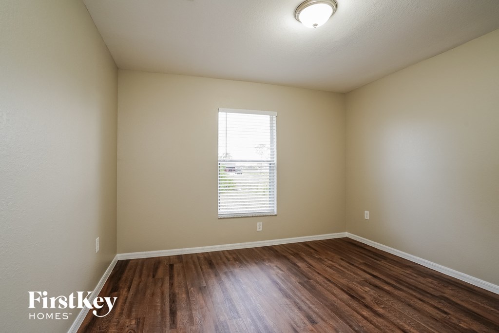 the living room of an empty house with wood flooring and a window