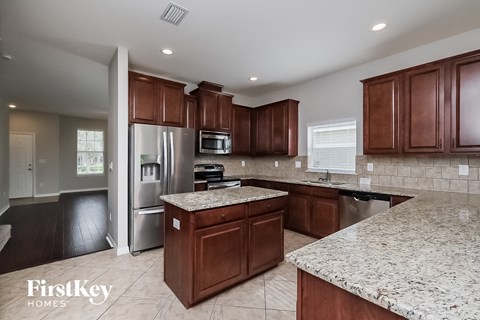 A kitchen with brown cabinets and granite countertops.