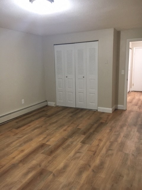 an empty living room with wooden floors and a closet