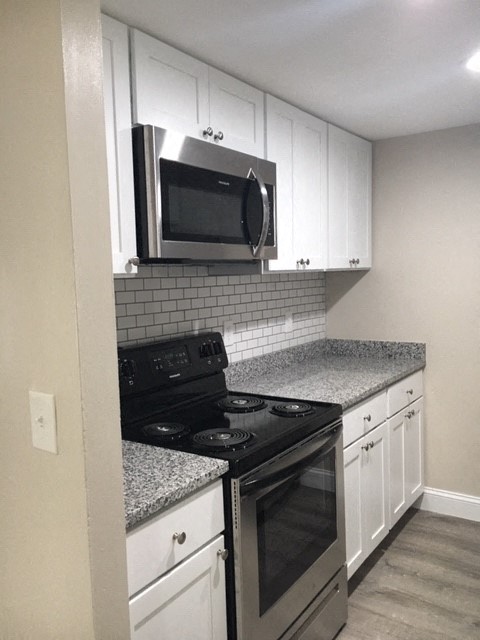 a kitchen with a stove microwave and white cabinets