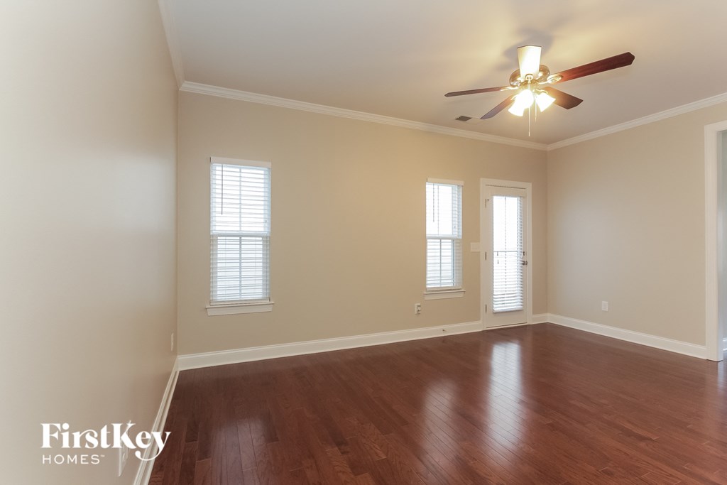 an empty living room with wood floors and a ceiling fan