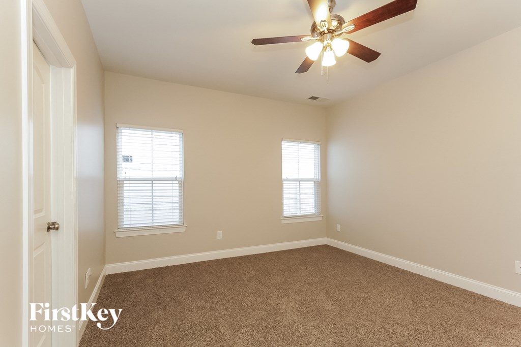 an empty room with a ceiling fan and two windows
