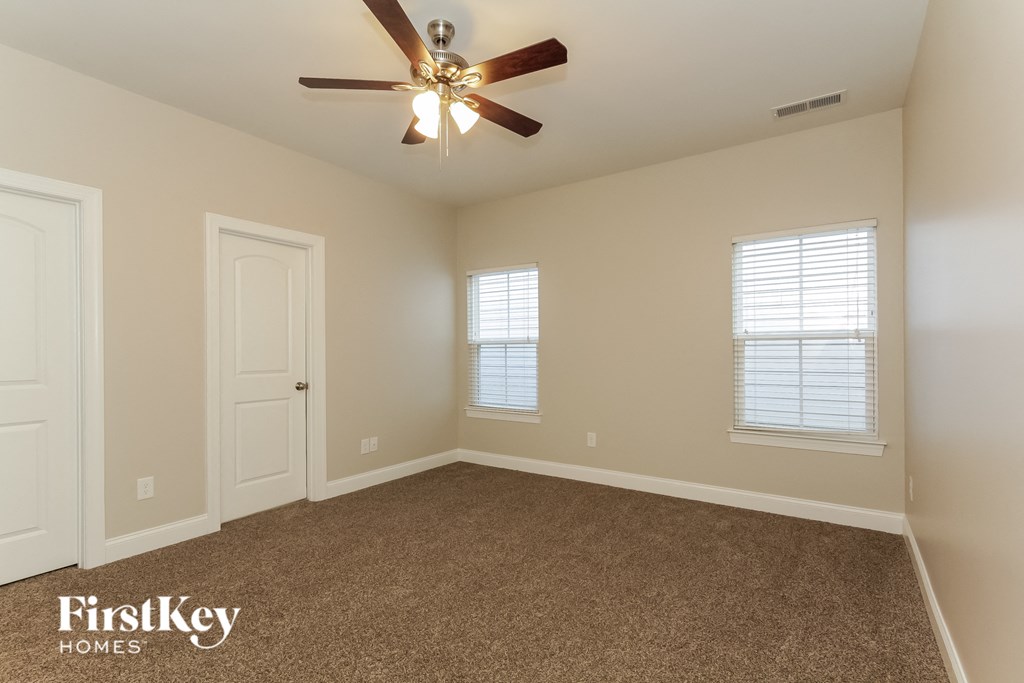 the master bedroom has a carpeted floor and a ceiling fan