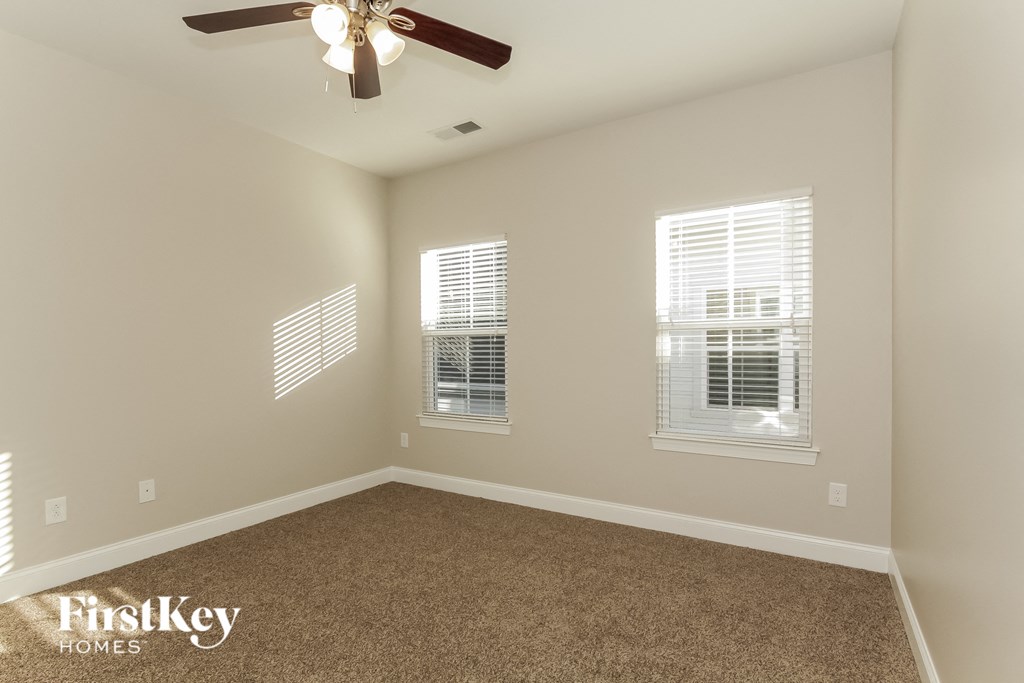 an empty bedroom with a ceiling fan and windows