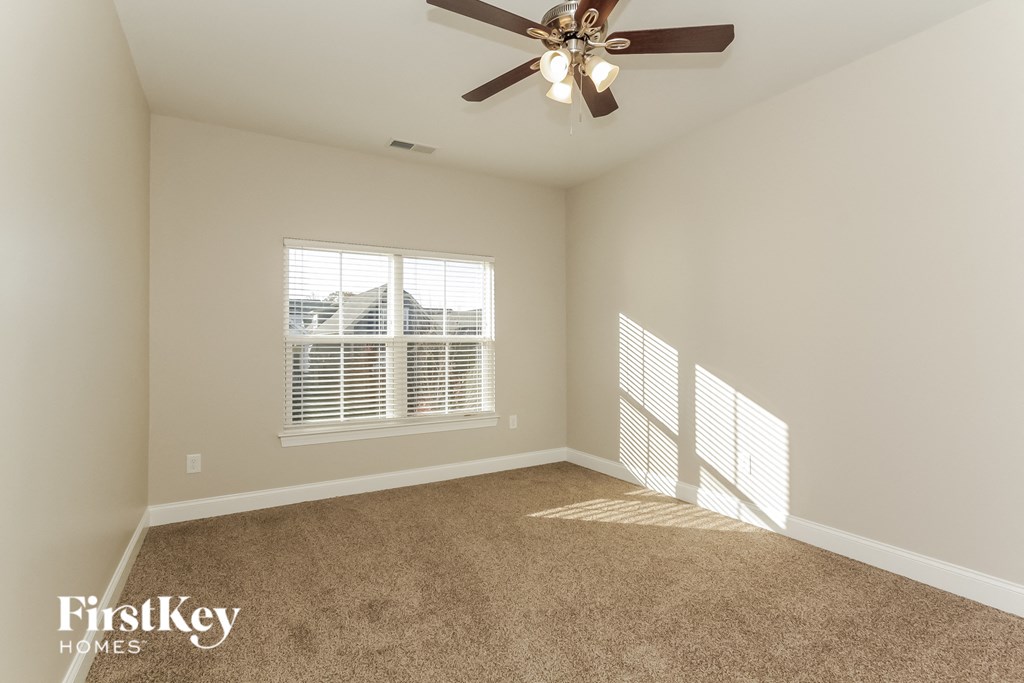an empty living room with a ceiling fan and a window