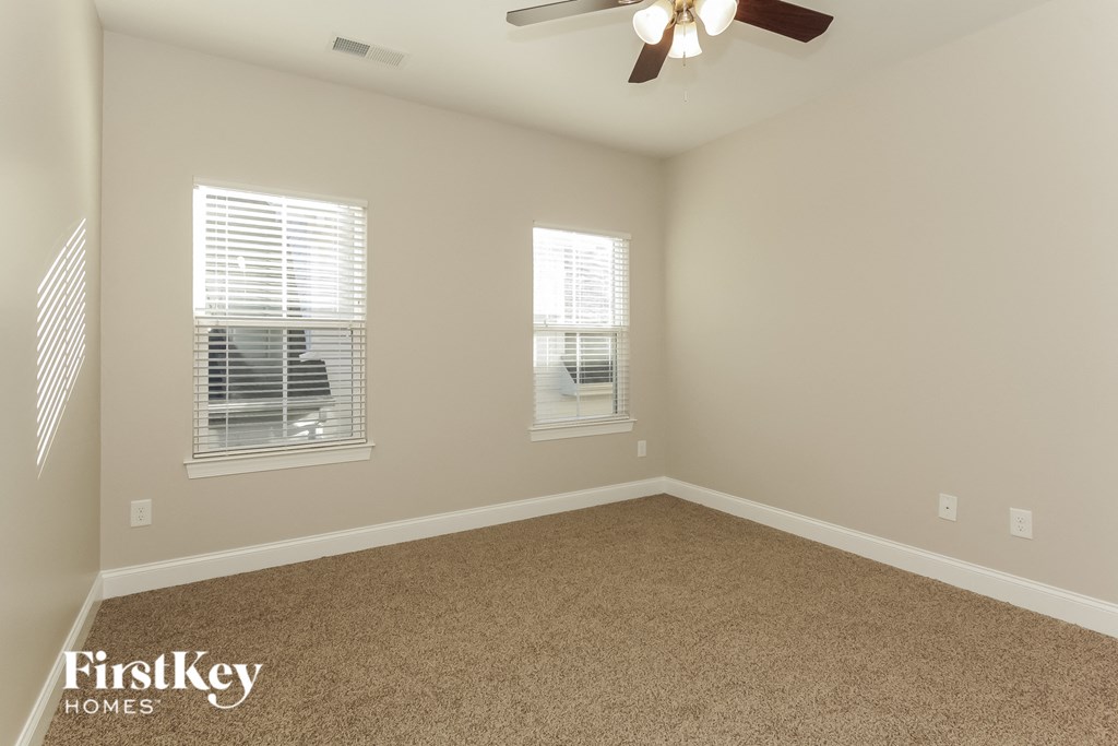 an empty room with a ceiling fan and two windows