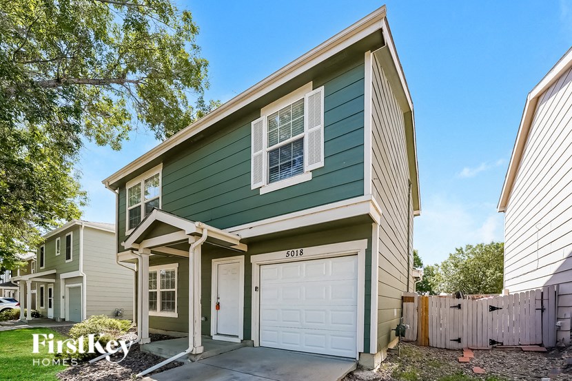 a green and white house with a white garage door