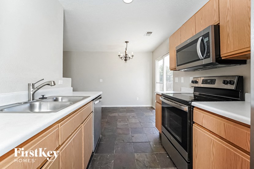 a kitchen with wood cabinets and black appliances and white counter tops