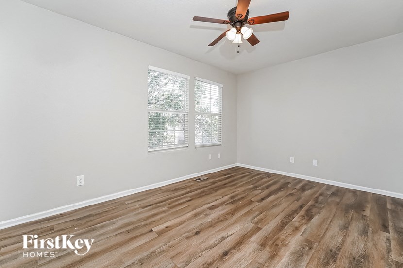 the living room of an empty house with wooden floors and a ceiling fan