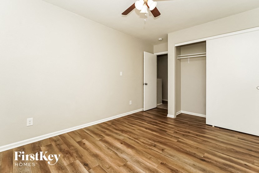 a bedroom with white walls and wood flooring and a closet