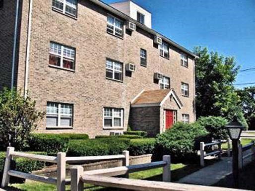 an old brick house with a red door and a wooden fence