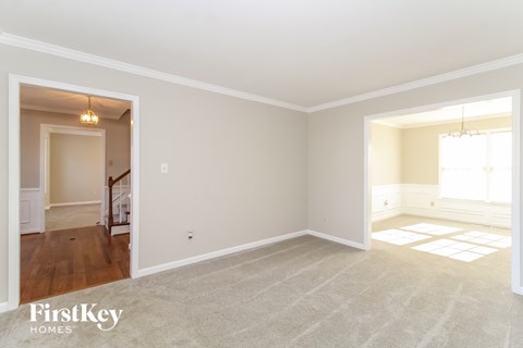 the living room and dining room of a home with white walls and carpet
