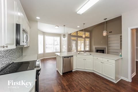 A kitchen with white cabinets and a wooden floor.