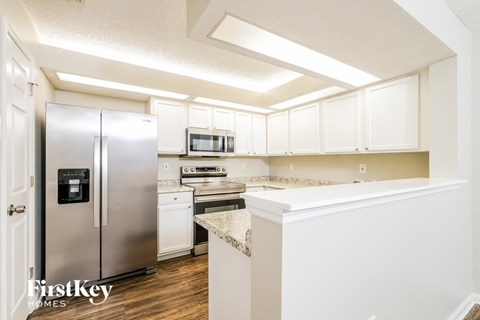 a kitchen with white cabinets and a stainless steel refrigerator