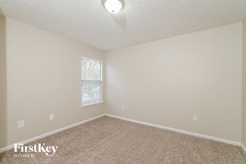 a spacious room with carpet and a window