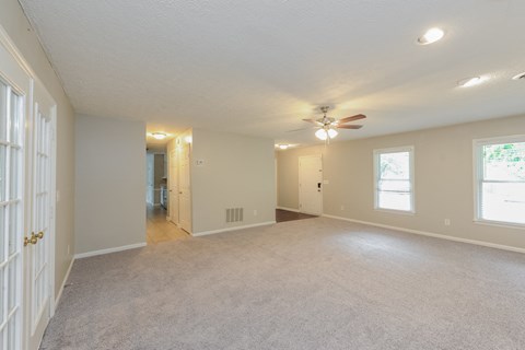 an empty living room with a ceiling fan