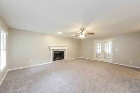 an empty living room with a fireplace and a ceiling fan