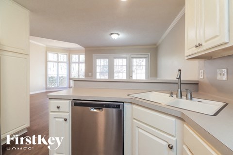A kitchen with a stainless steel dishwasher and white cabinets.